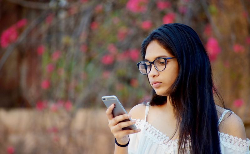A young woman reading her phone among flowers