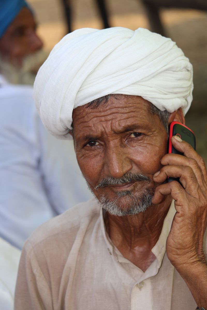 An elderly man in a turban listening on his phone